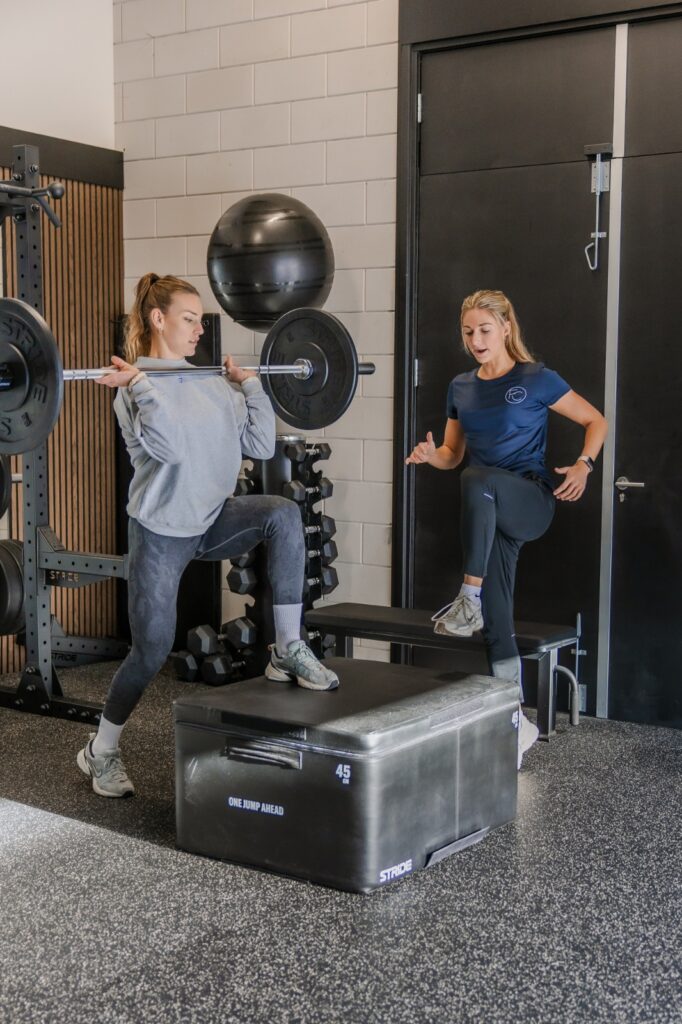Twee sporters trainen met een medicinebal en een box in de studio van Forge Coaching