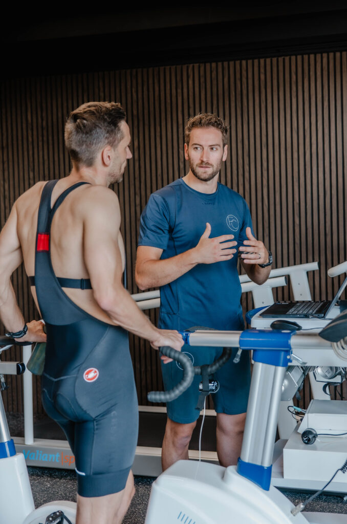 Jorrick bespreekt de resultaten met een sporter naast de fietsergometer