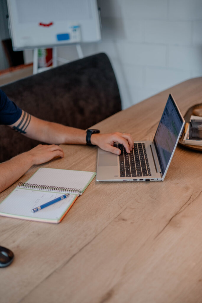 Trainingsplan op een laptop en notitieblok bij online coaching
